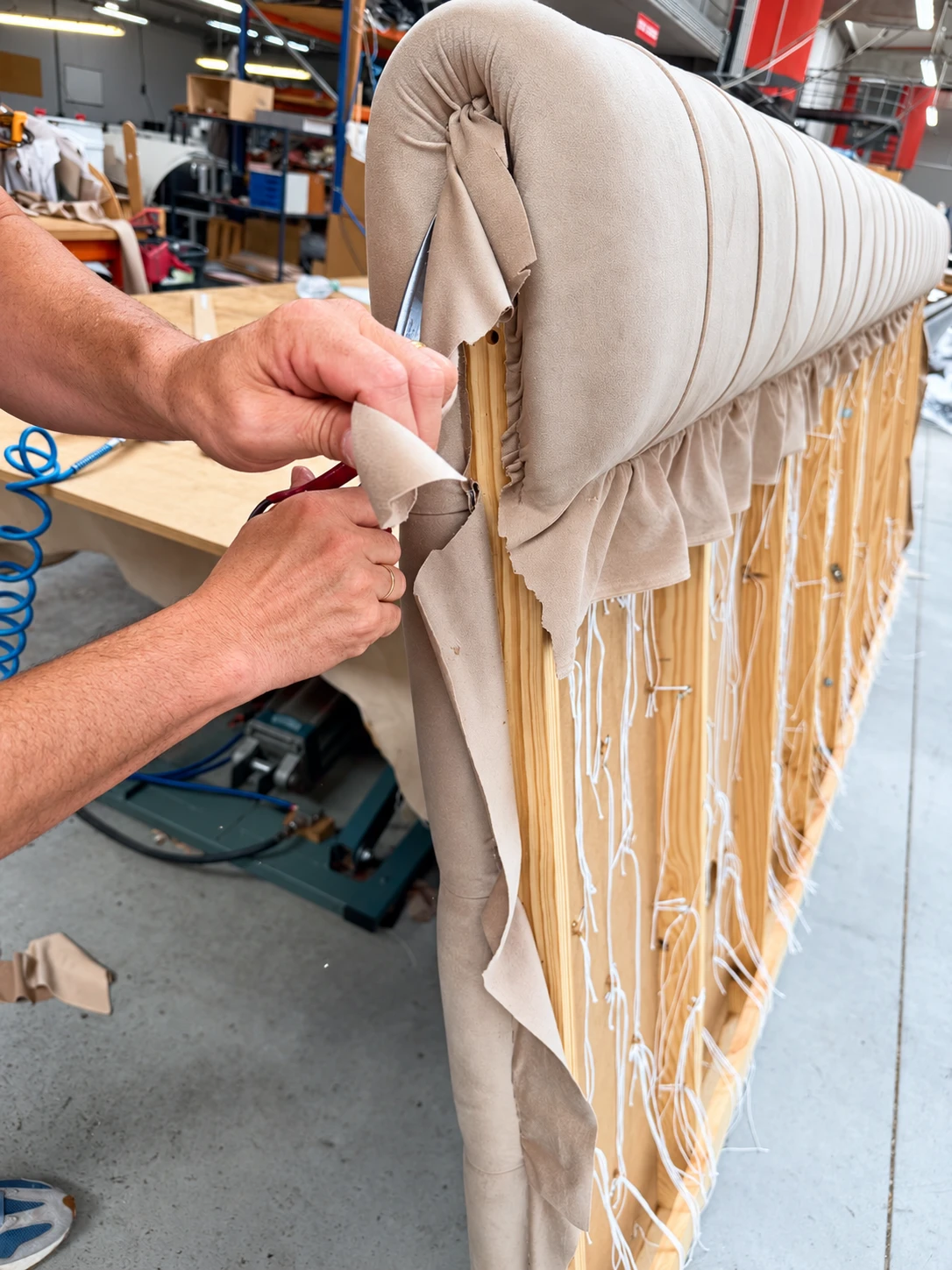 Upholsterer trimming fabric on a headboard